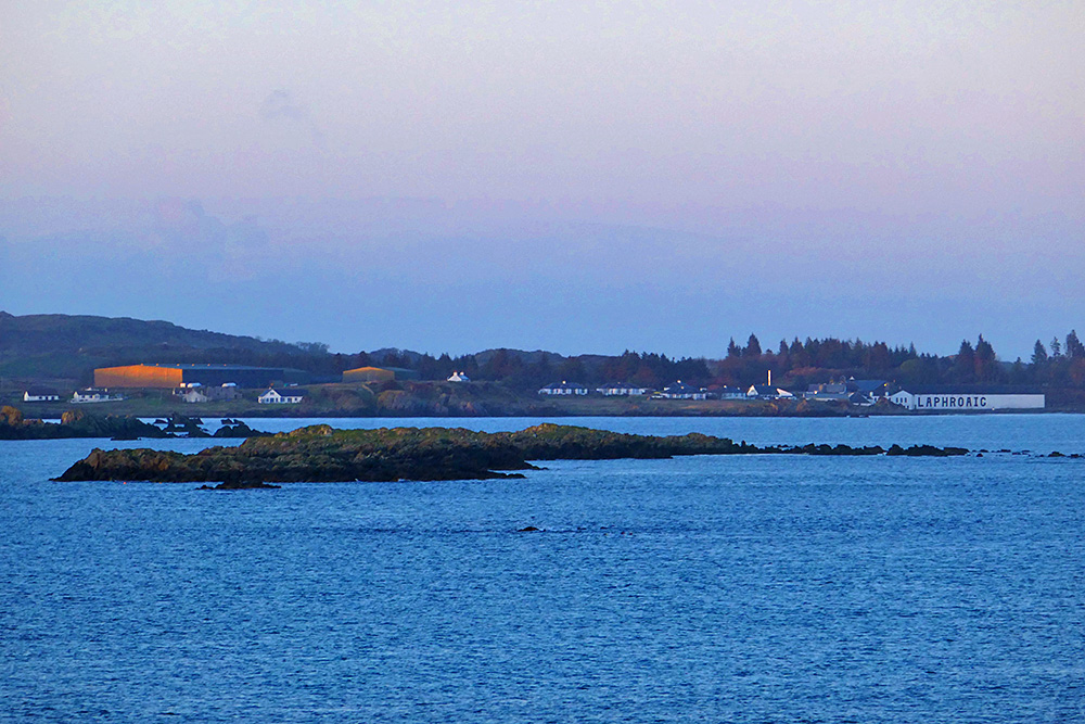 Picture of a coastal distillery (Laphroaig on Islay) seen from a passing ferry in the evening light