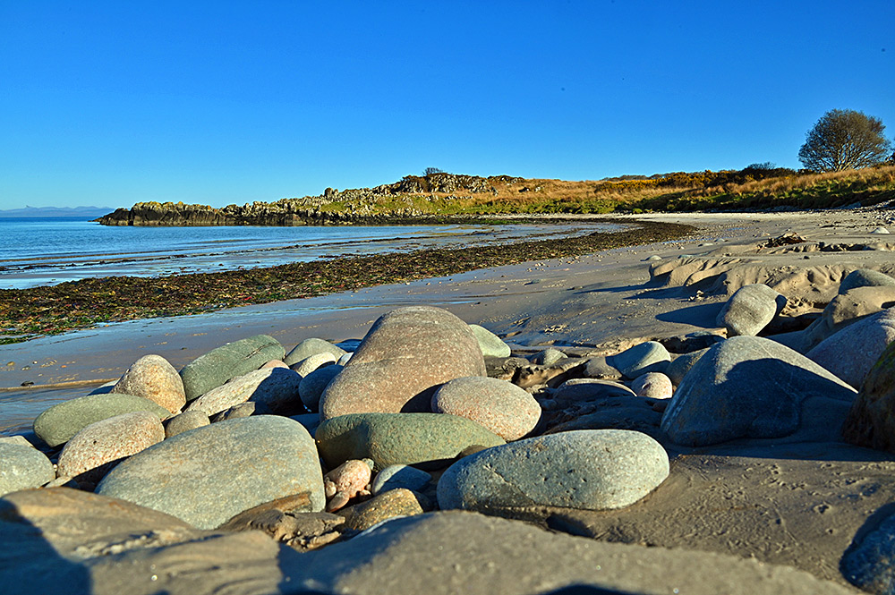 Picture of a pebble beach merging into a sandy beach at the end of a bay