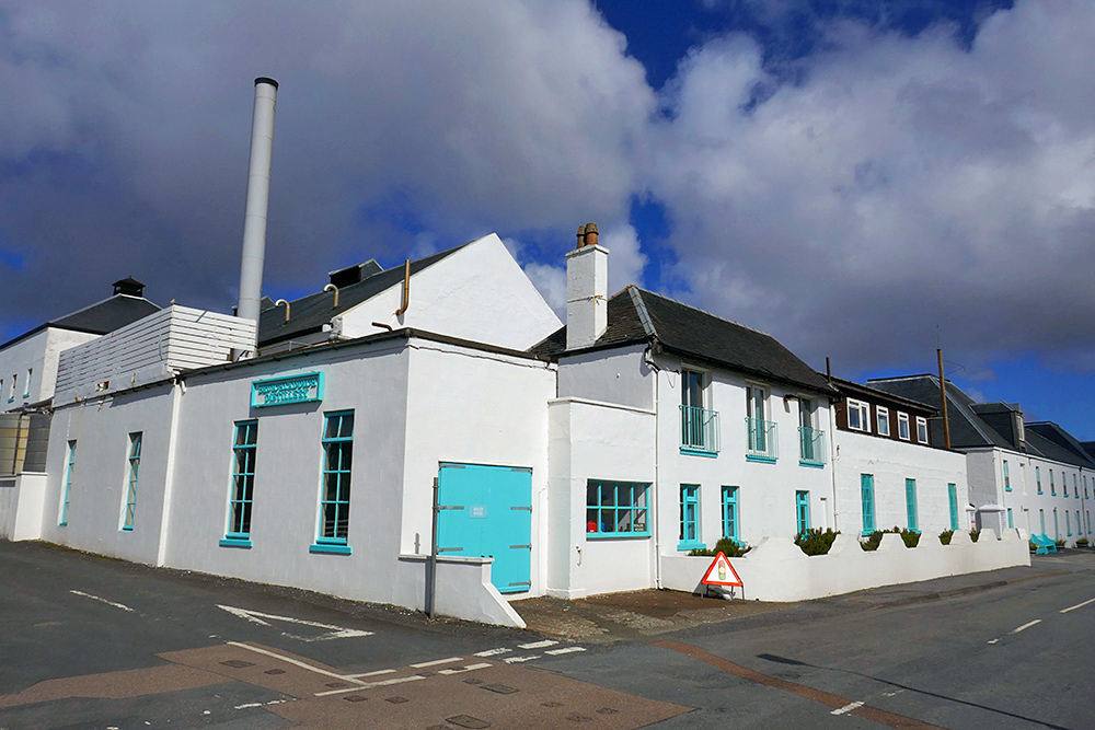 Picture of Bruichladdich distillery in bright sunshine with some moody clouds in the background