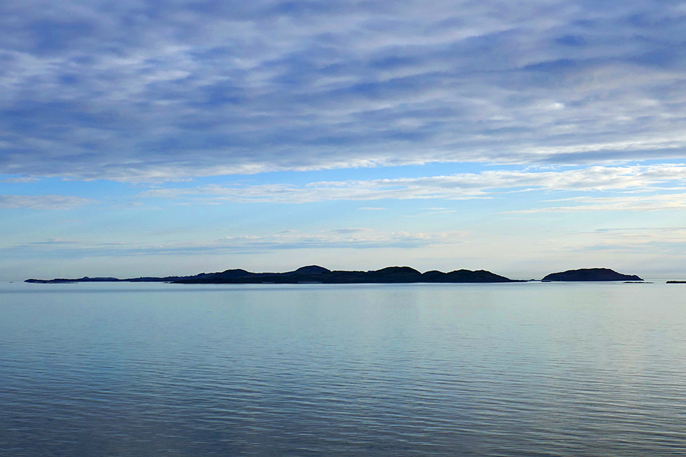 Picture of the silhouette of an island in a calm sea on a spring evening