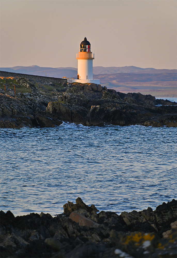 Picture of a small lighthouse on a rocky shore in mild April evening sunshine