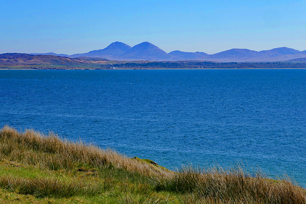 Picture of two mountains seen across a sea loch from a grassy shore