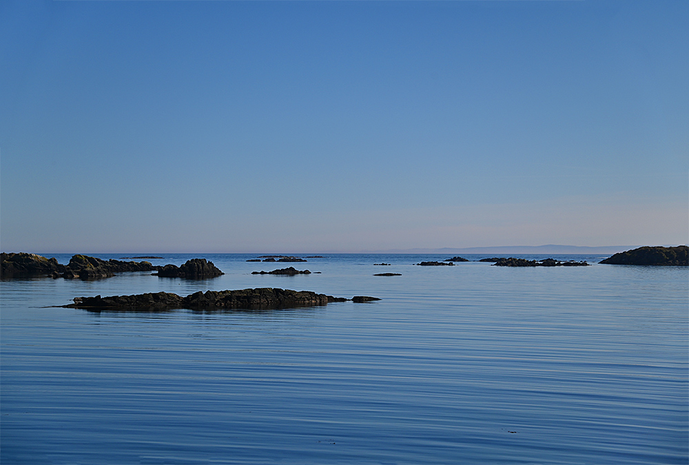 Picture of a wide bay with rocks scattered around it on a calm sunny April afternoon