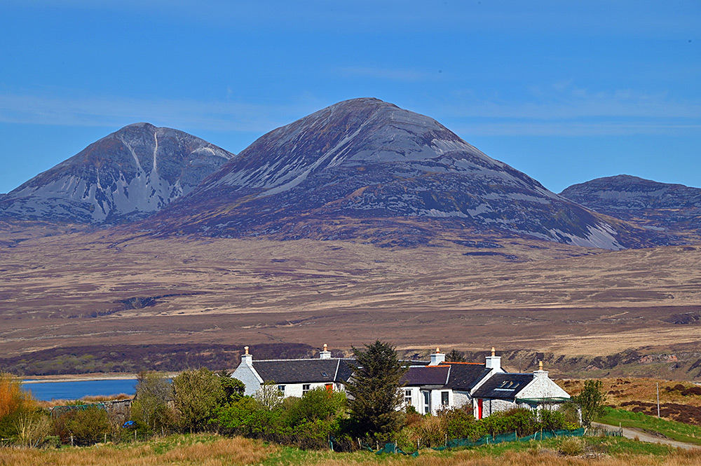 Picture of some whitewashed cottages below some mountains on the other side of a sound between two islands