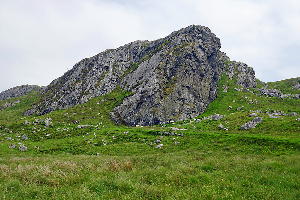 Picture of some steep rocky crags above a track going up a hillside