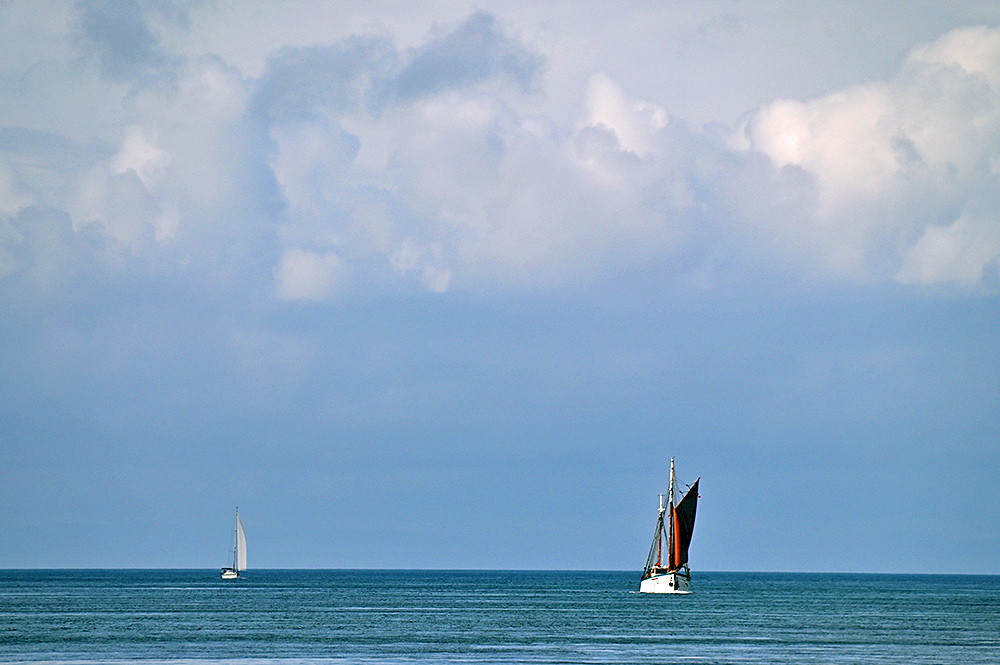 Picture of the ketch Fleur de Lampaul and a modern sailing yacht on a flat sea with clouds above