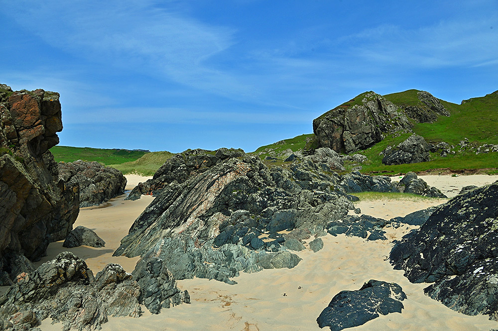 Picture of a variety of rocks and boulders at the end of a sandy beach
