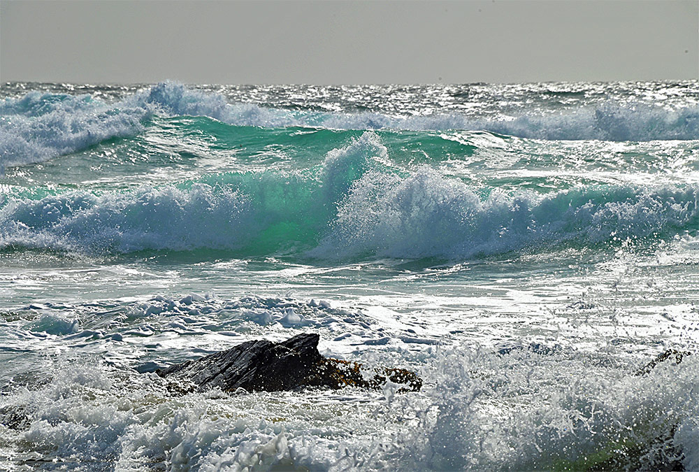 Picture of a small rock surrounded by breaking waves