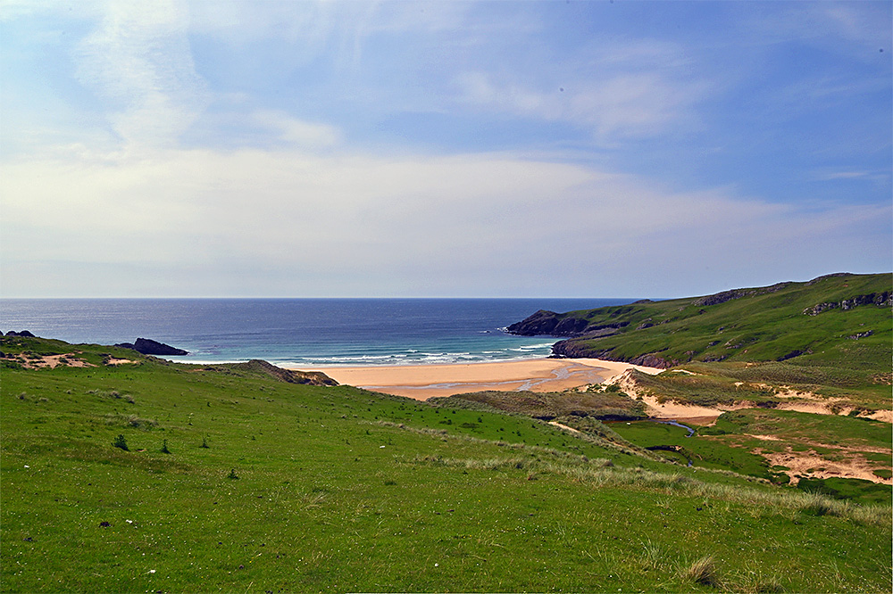 Picture of a view from some tall dunes over a bay with a sandy beach